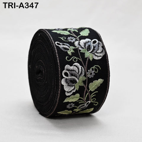 A black fabric with a floral embroidered design in shades of green and white.