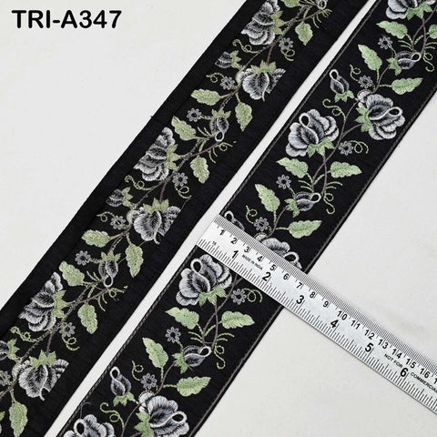 a close-up view of a black and white floral embroidered fabric, with a ruler placed on top of it to measure its length.