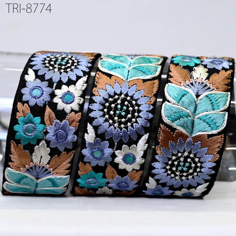 three decorative fabric pieces with intricate floral embroidery in various shades of blue, green, and brown. The pieces appear to be made of a shiny material, possibly silk or satin, and are arranged in a row.