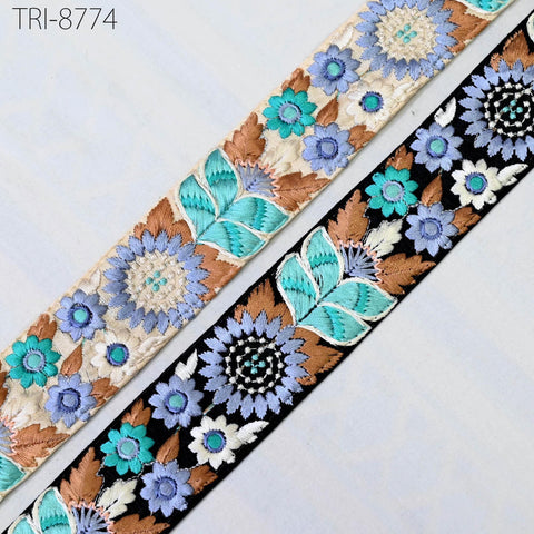 two spools of embroidered fabric with floral designs in shades of blue, brown, and white.