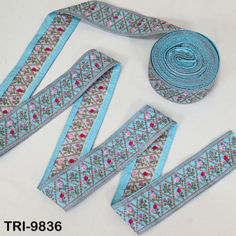 a collection of blue and green embroidered fabric pieces, including a rolled-up piece of fabric with a similar pattern.