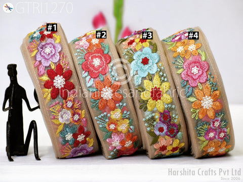 four decorative fabric pieces with colorful floral embroidery, arranged in a row on a surface.