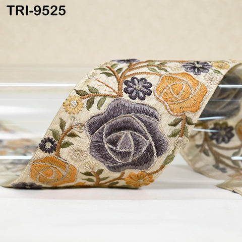 a decorative fabric with a floral pattern, including roses and other colorful flowers. The fabric appears to be a decorative ribbon or textile, with a beige background.