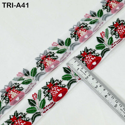 a close-up view of a decorative ribbon with a repeating pattern of red and green leaves and flowers, along with a ruler placed next to it.