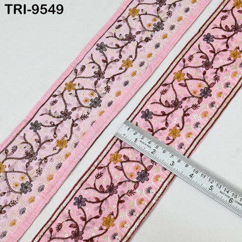 two pieces of fabric with intricate floral embroidery in shades of pink and burgundy. A ruler is placed between the two pieces of fabric, indicating the size or length of the fabric.