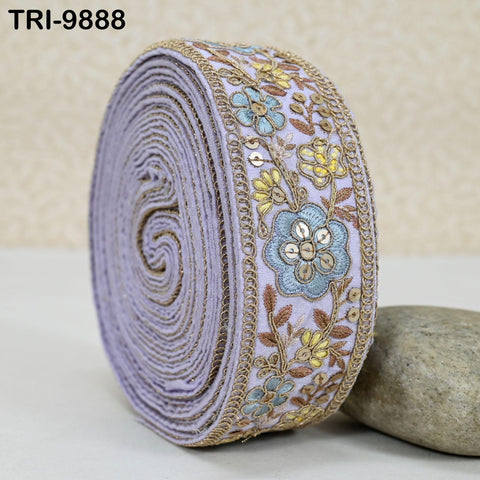 A close-up image of a decorative purple fabric with a floral pattern, featuring a repeating floral motif and a metallic border.