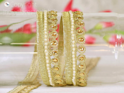 A close-up view of a gold-colored, intricately designed bracelet with a floral pattern on the beads.