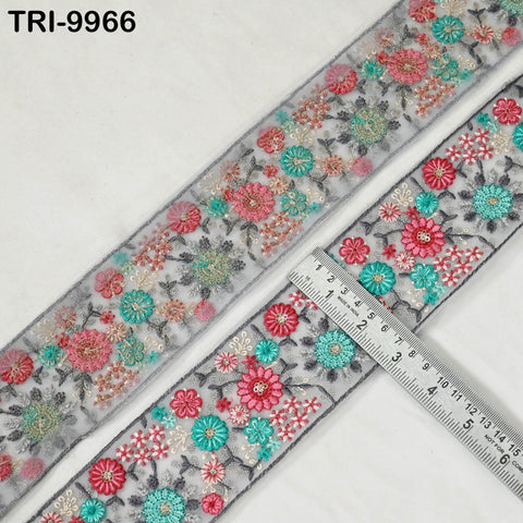 a decorative fabric with a floral pattern, featuring a variety of colorful flowers and leaves. The fabric appears to be a decorative trim or border, and a ruler is placed next to it to measure its length.