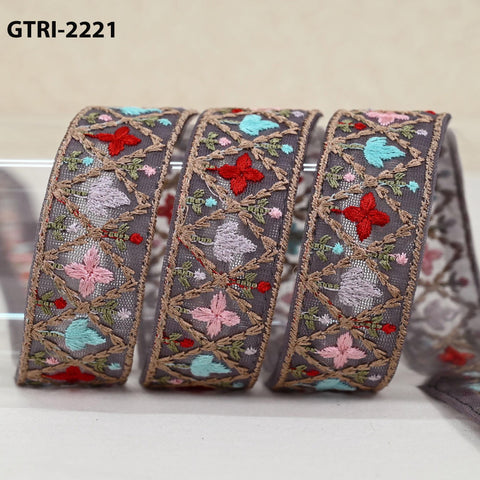 A close-up image of a decorative fabric with a floral pattern, featuring a repeating design of red and pink flowers against a gray background.
