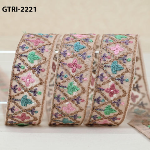 A close-up image of a decorative beige ribbon with intricate floral embroidery in various shades of pink, green, and purple.