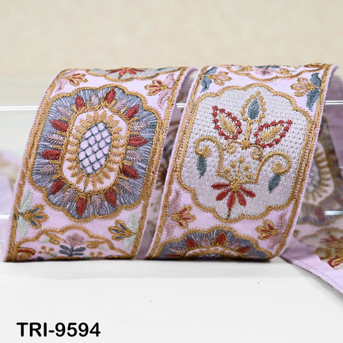 a decorative fabric with intricate embroidered patterns in shades of pink, blue, and gold.
