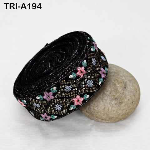 a black fabric with a floral pattern, placed on a white surface next to a gray rock.
