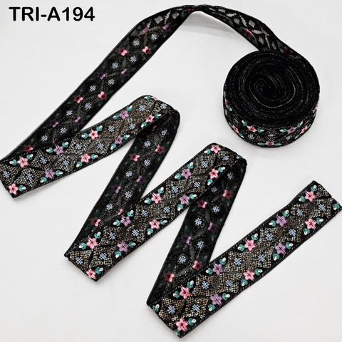 a spool of black lace ribbon with a floral pattern, and a piece of the same ribbon.