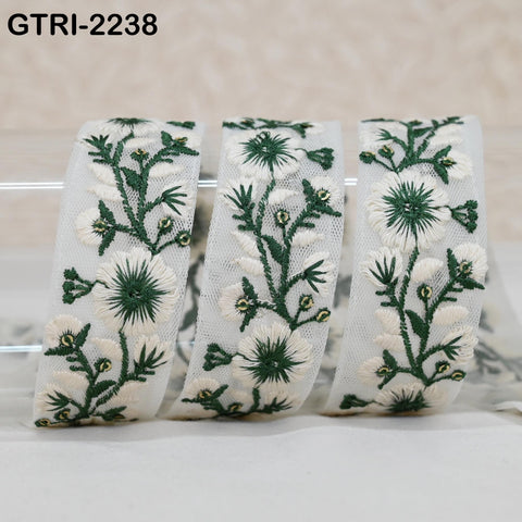 three white fabric pieces with green floral embroidery designs, arranged in a row.