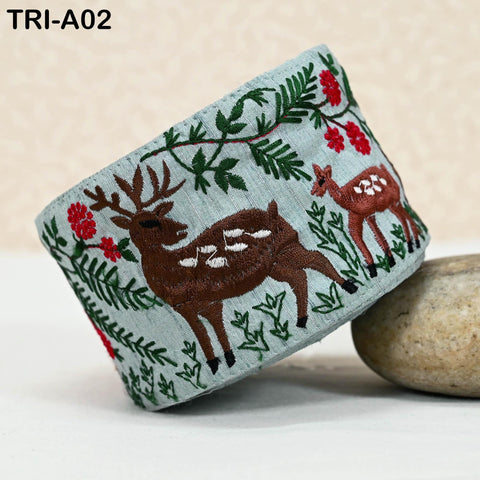 A decorative fabric with a floral pattern and embroidered deer images, including a brown deer and a white deer, is displayed on a surface.