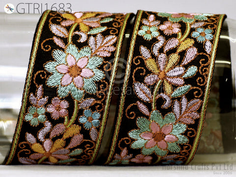 two ornate, decorative fabric pieces with intricate floral embroidery in shades of green, pink, and yellow. The pieces appear to be made of a dark fabric, possibly black, and are displayed against a white background.