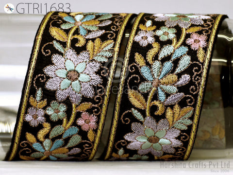 two ornate, decorative fabric pieces with intricate floral embroidery in shades of black, gold, and pink. The pieces appear to be made of a shiny material, possibly silk or satin, and are displayed against a plain background.