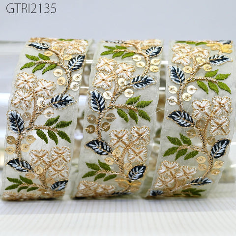 three decorative fabric pieces with intricate floral and leaf patterns in shades of green, white, and gold. The pieces appear to be made of a light-colored material, possibly silk or chiffon, and are arranged in a row.