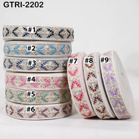 A stack of colorful spools of embroidered ribbon, each with a unique pattern and color, arranged in a visually appealing manner.