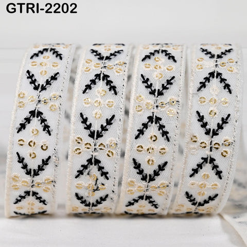 A close-up image of a decorative ribbon with a repeating pattern of black and gold floral designs.