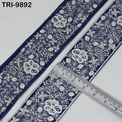 two pieces of blue fabric with white floral embroidery, and a ruler is placed between them, indicating the size of the fabric.