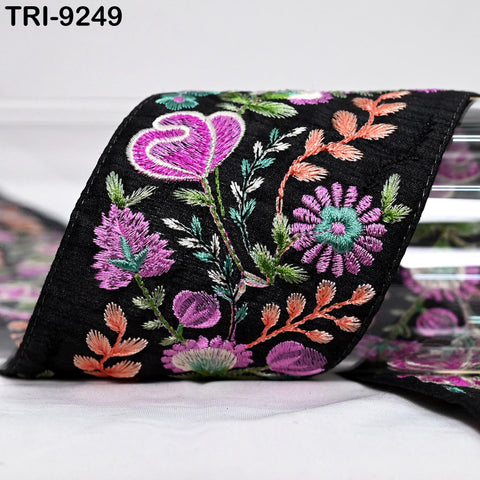 a close-up view of a black fabric adorned with a vibrant floral pattern, including pink, purple, and green flowers and leaves.