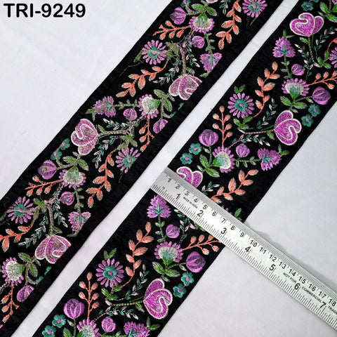 two pieces of black fabric with a floral embroidered design in shades of purple and green. A ruler is placed on top of the fabric, indicating the size of the fabric.