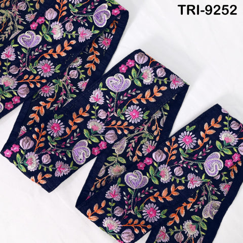 a close-up view of a decorative fabric with a floral pattern in shades of blue, purple, and orange. The fabric appears to be a piece of embroidered material, possibly used for clothing or home decor.