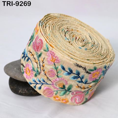 A rolled-up fabric with a floral pattern, featuring pink and green flowers, is displayed against a white background.