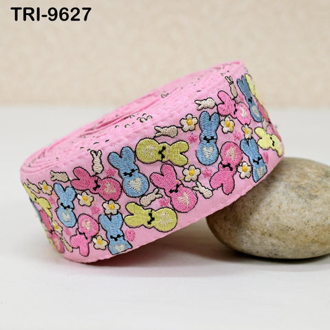 A pink fabric with a playful bunny pattern is shown, with a rock and a light-colored object placed next to it.
