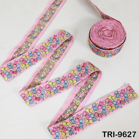 a collection of pink and yellow ribbons with a playful, cartoon-like pattern. There is also a spool of pink ribbon in the background.
