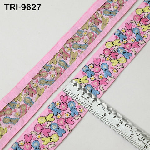 a pink fabric with a repeating pattern of cartoon rabbit characters, and a ruler is placed on top of the fabric to measure its length.