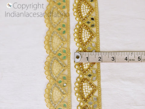 two pieces of gold and green embroidered fabric with a measuring tape placed between them, indicating the size of the fabric.