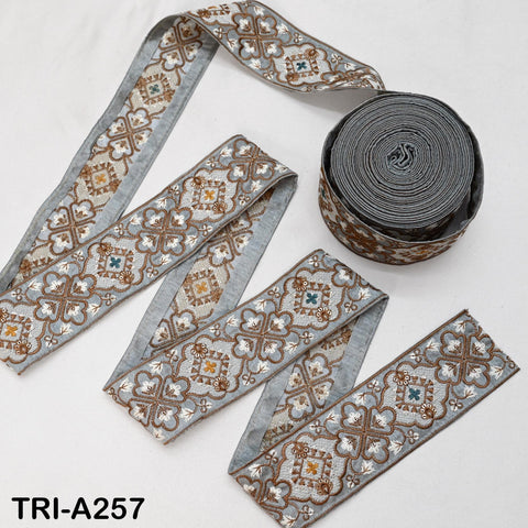 a collection of decorative fabric pieces, including a gray and brown patterned fabric and a spool of gray fabric with a similar pattern.