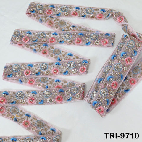 a collection of decorative fabric pieces with intricate floral patterns in shades of pink and blue. The fabric appears to be made of a shiny material, possibly sequin or beads, and is arranged in a zigzag pattern on a white background.