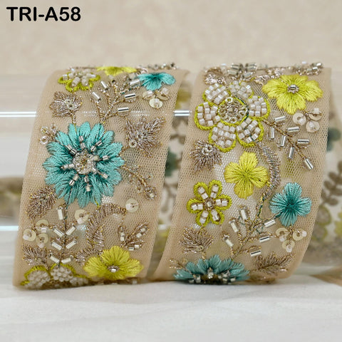 two beige fabric pieces adorned with intricate floral embroidery in shades of blue and yellow, including flowers, leaves, and beads.