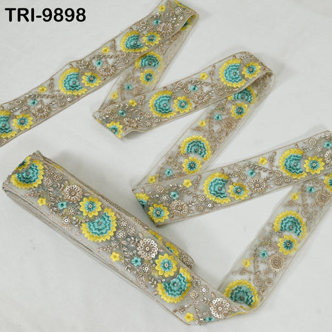 a decorative fabric with a floral pattern in shades of yellow and green. The fabric appears to be a decorative trim or ribbon, with a repeating floral design.