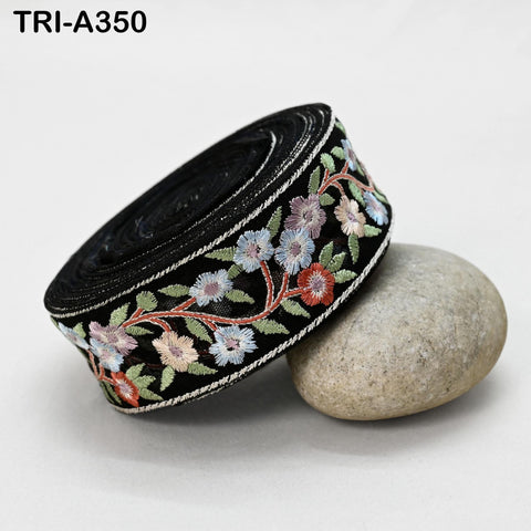 A black, floral-patterned ribbon is lying on a gray rock, with a black band around the ribbon.