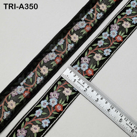 a decorative black ribbon with a floral pattern, and a ruler is placed on top of it, indicating the ribbon's size.