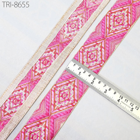 a close-up view of a decorative fabric with a pink and white geometric pattern. A ruler is placed next to the fabric, indicating its size or dimensions.