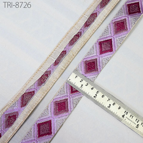 a close-up view of a decorative fabric with a repeating diamond pattern in shades of pink and white. A ruler is placed on the fabric, indicating its size.