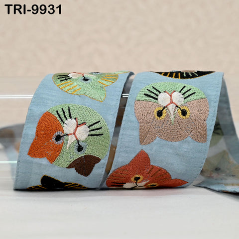 a pair of blue fabric ribbons with colorful cat embroidered designs on them.