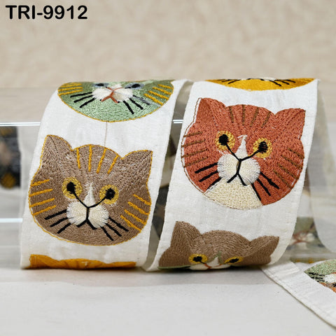 a pair of white fabric rolls with colorful cat embroidered designs on them.
