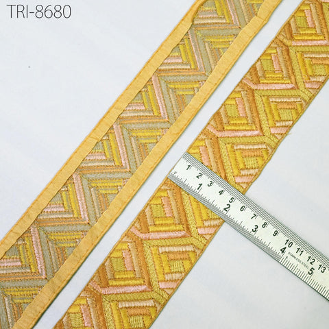 a close-up view of a decorative fabric with a zigzag pattern in shades of yellow and orange. A ruler is placed next to the fabric, indicating its size.
