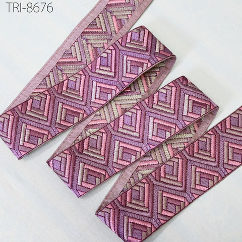 a collection of pink and purple geometric patterns on fabric, including a pink and purple geometric patterned ribbon.