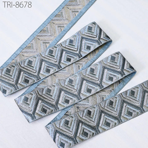 a set of decorative fabric pieces with a geometric pattern in shades of blue and gray. The pieces appear to be made of a shiny material and are arranged in a row on a white surface.