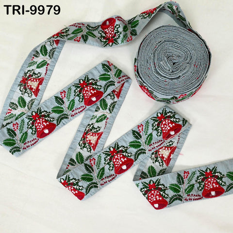 a spool of grey ribbon with a floral pattern and a spool of grey ribbon with a red and green floral pattern, both sitting on a white surface.