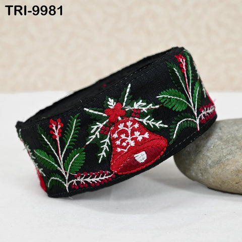 A black and red embroidered band with a bell design, resting on a gray rock.