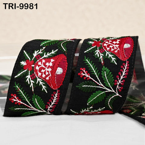 a close-up view of a decorative ribbon with a floral pattern in red and green colors. The ribbon appears to be black and has a repeating pattern of red flowers and green leaves.