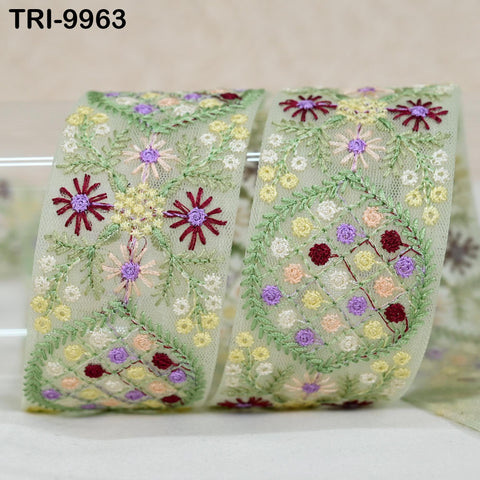 a decorative fabric with a floral pattern, including various flowers and leaves in different colors such as red, yellow, and purple. The fabric appears to be a ribbon or a piece of cloth with a floral motif.